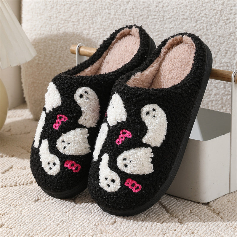 Black slippers with ghost and bow design on a soft surface