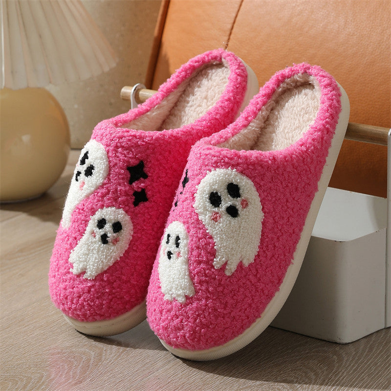 Pink slippers with ghost designs on a wooden floor.