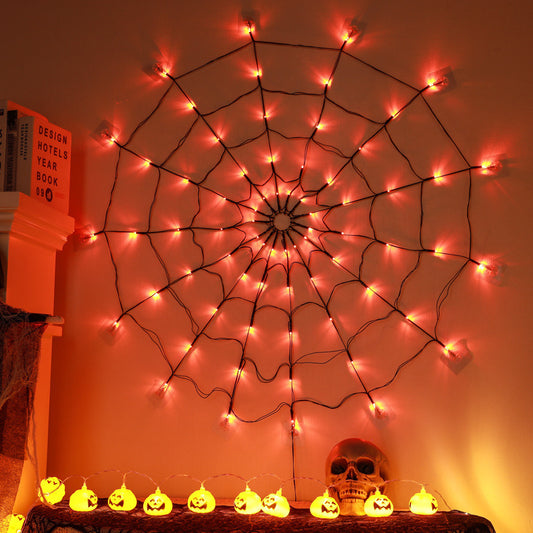Spider web decoration with lights on a wall, Halloween-themed decorations below.